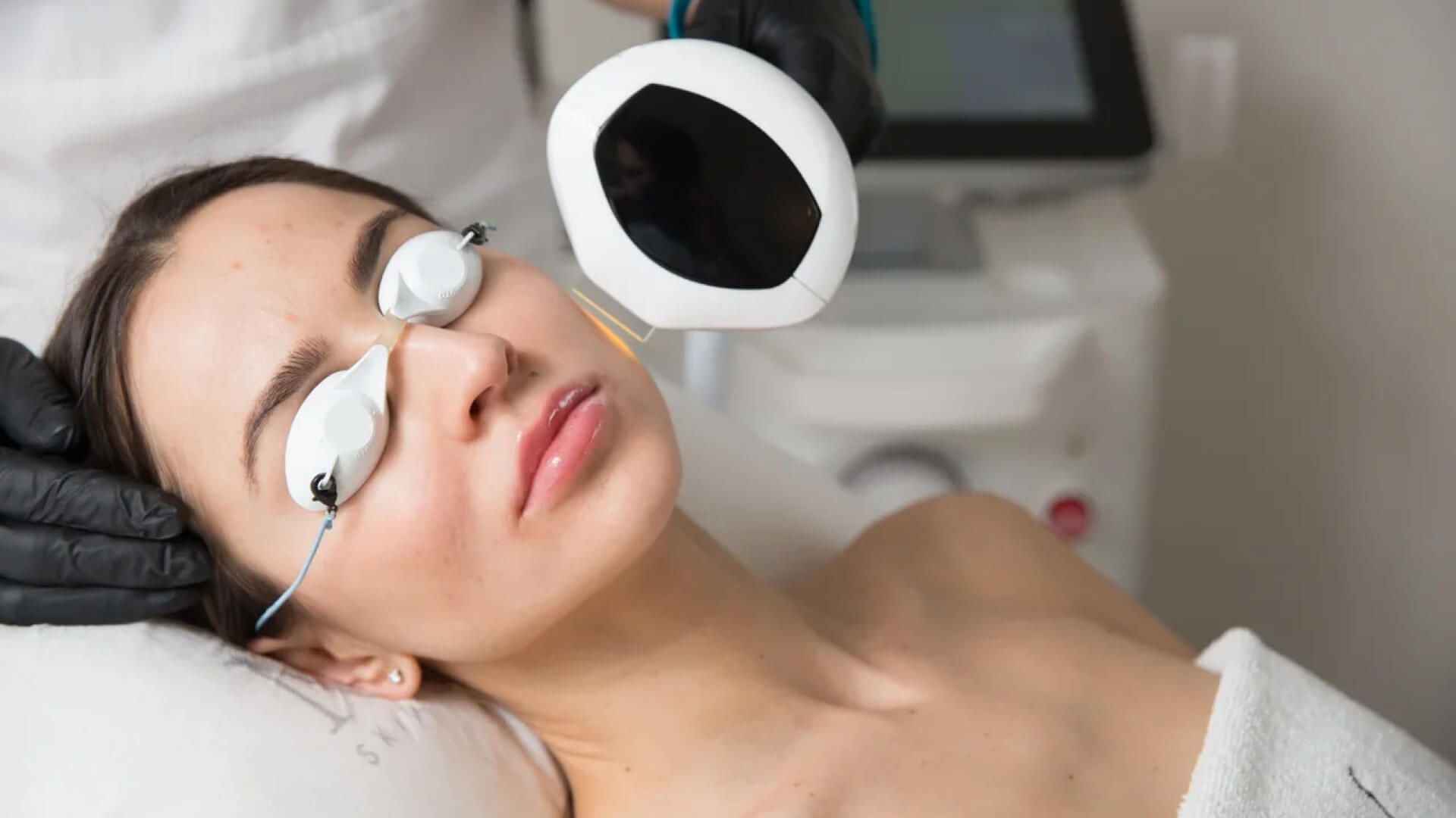 A woman, with eye protection, receiving lumecca treatment on her face