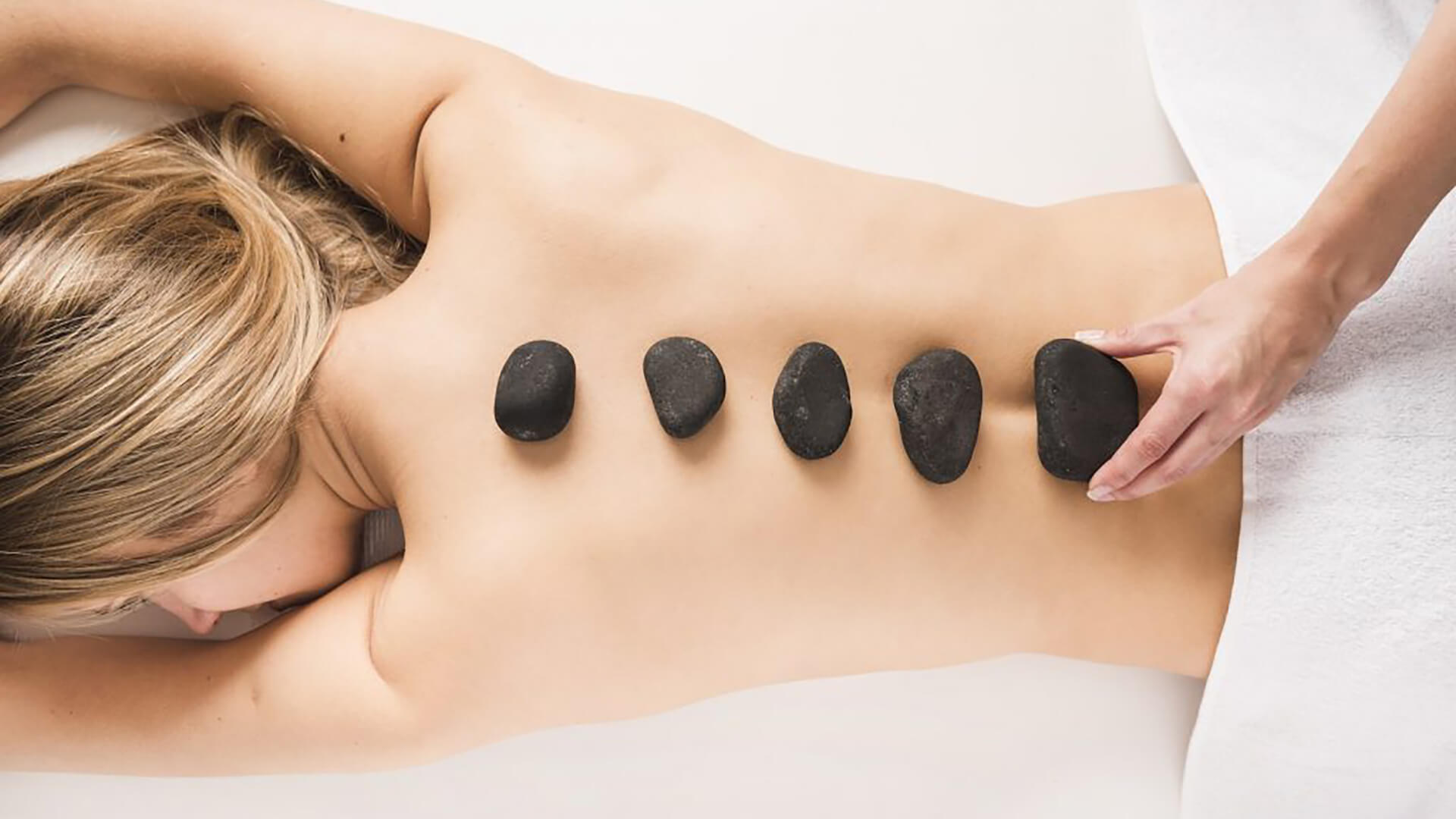 A woman with hot stones being placed on her back